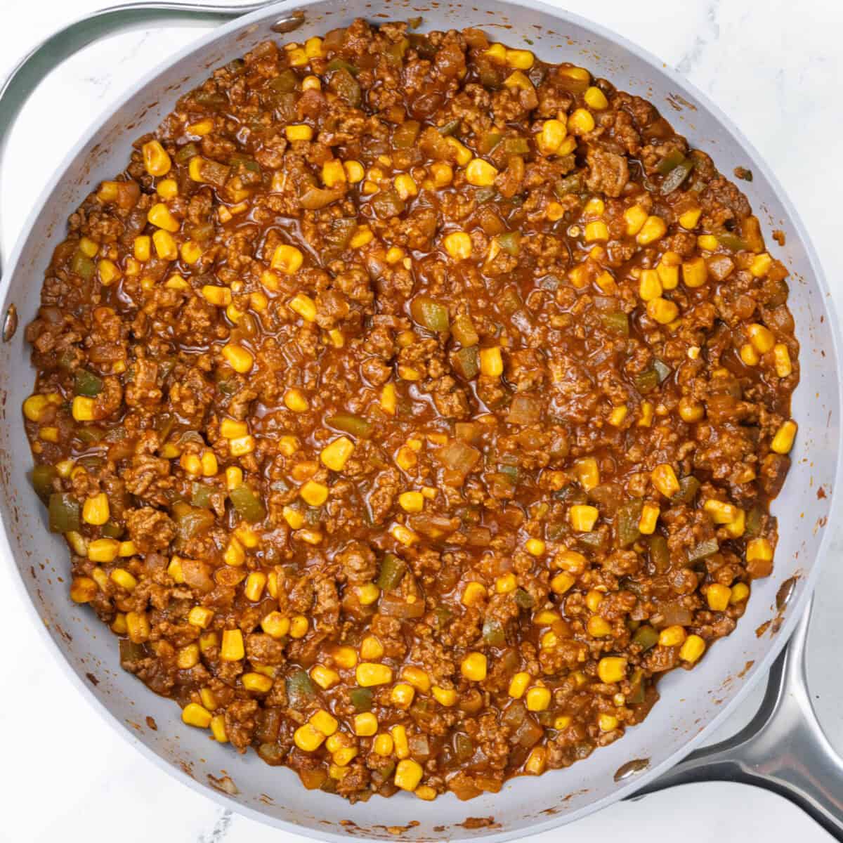 cooked meat and veggies with corn in pan