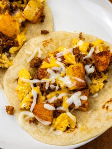 close up of finished Chorizo Potato Egg and Cheese Breakfast Tacos on a white plate