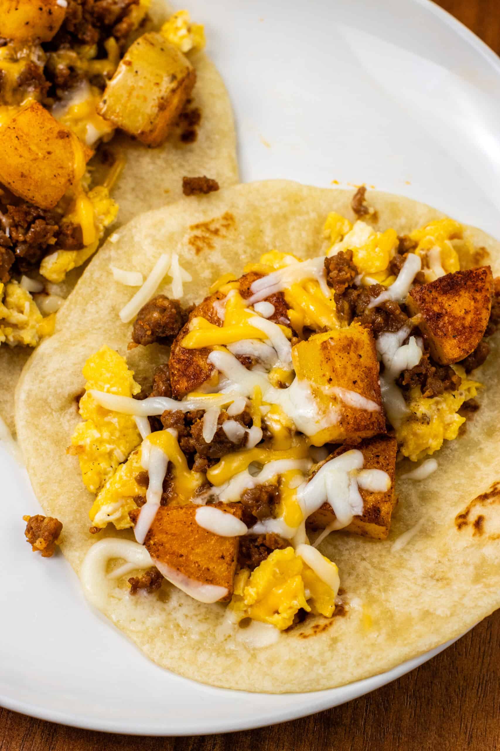 close up of finished Chorizo Potato Egg and Cheese Breakfast Tacos on a white plate