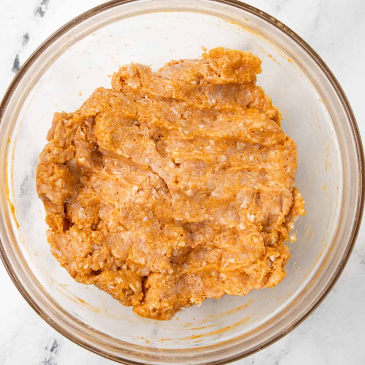 chicken mixed in bowl for Buffalo Ground Chicken Burger with Whipped Goat Cheese