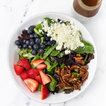 Summer Berry Salad with Feta and Candied Pecans in a bowl with vinaigrette