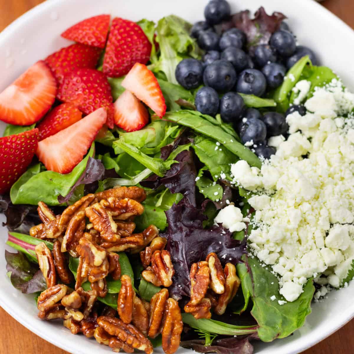 Summer Berry Salad with Feta and Candied Pecans finished in a bowl close up