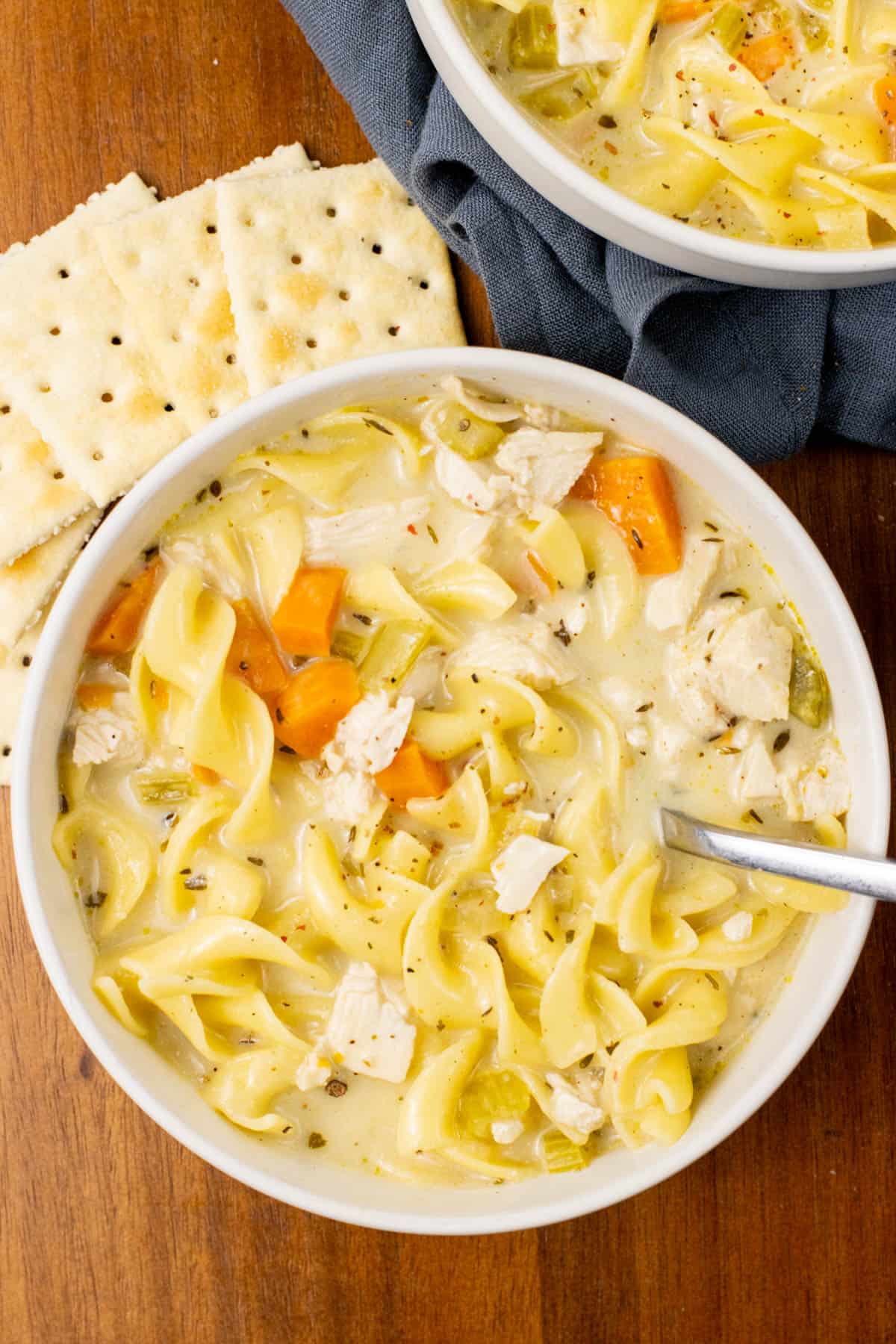 chicken noodle soup in a bowl with crackers on the side